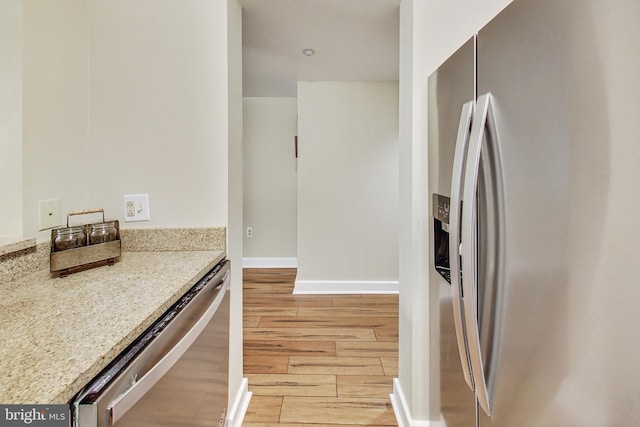 kitchen with light stone countertops, stainless steel appliances, and light wood-type flooring