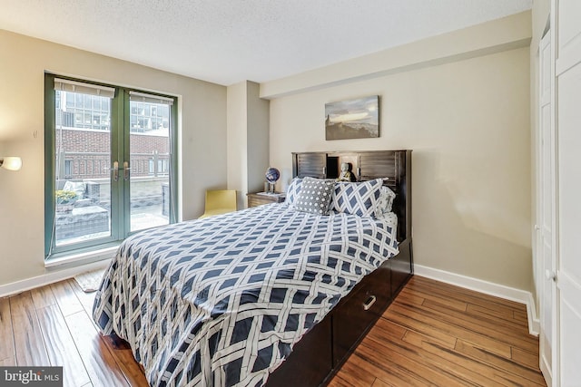 bedroom featuring a closet, wood-type flooring, a textured ceiling, and french doors