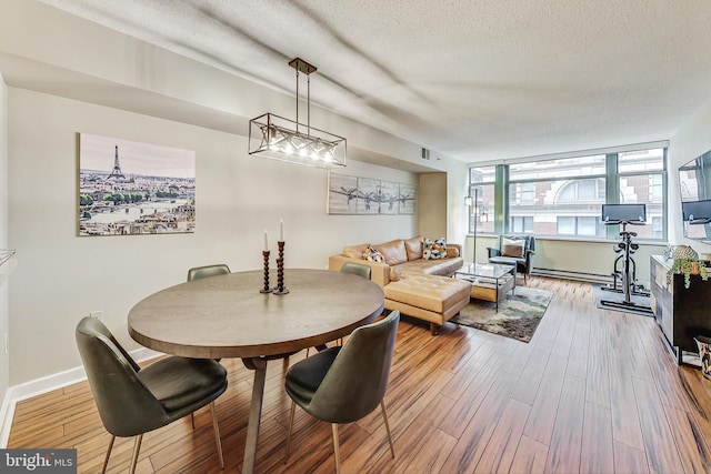 dining area with a textured ceiling, baseboard heating, and hardwood / wood-style flooring