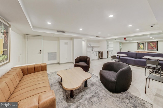 living room with wine cooler, a tray ceiling, and sink