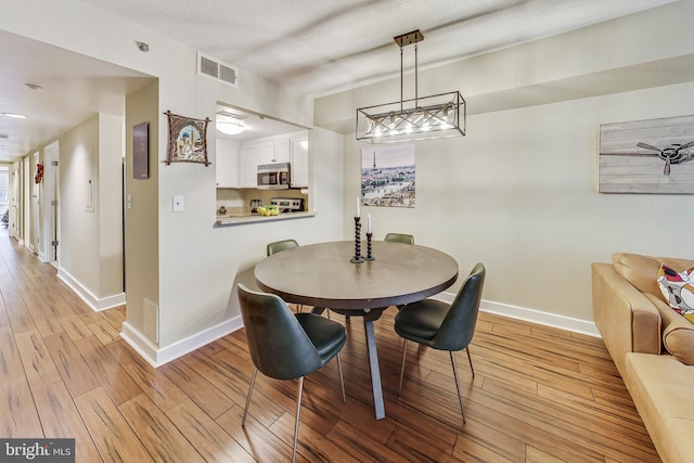 dining room with light wood-type flooring and a textured ceiling