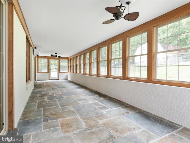 unfurnished sunroom featuring ceiling fan and a wall mounted air conditioner