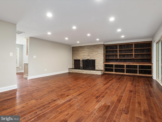 unfurnished living room featuring dark hardwood / wood-style floors and a stone fireplace