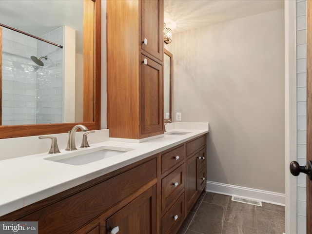 bathroom featuring tile patterned flooring, a tile shower, and vanity