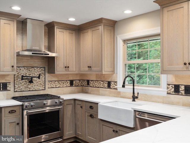 kitchen featuring appliances with stainless steel finishes, wall chimney exhaust hood, sink, and tasteful backsplash