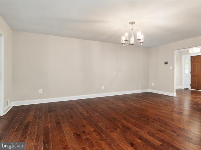 empty room featuring a chandelier and dark wood-type flooring