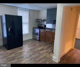 kitchen featuring ventilation hood, dark hardwood / wood-style floors, electric stove, and black fridge