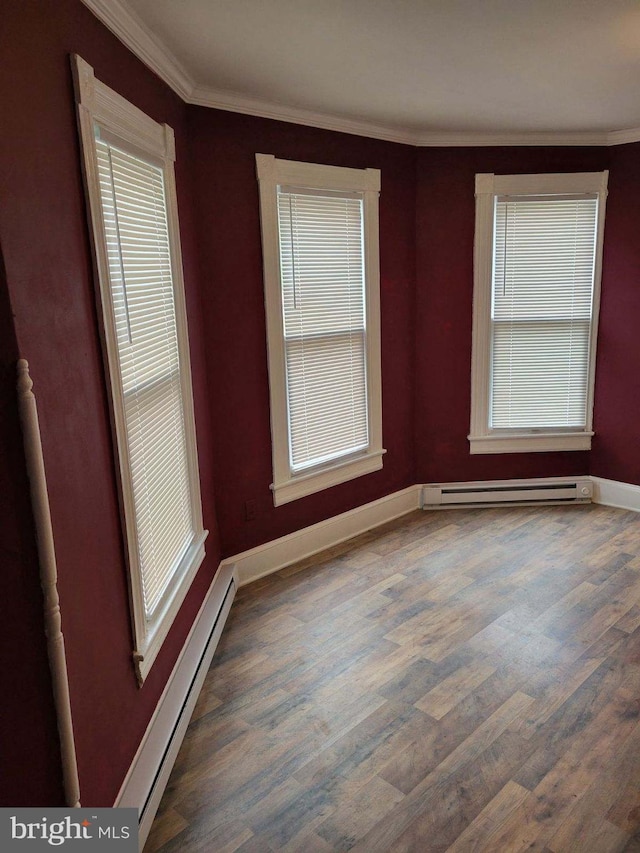 spare room with ornamental molding, baseboard heating, and dark wood-type flooring