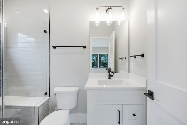 bathroom with a tile shower, vanity, and toilet