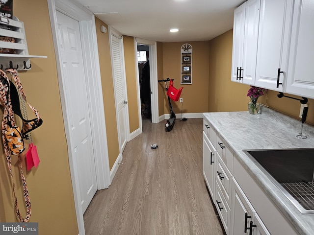 laundry area with light hardwood / wood-style flooring and sink