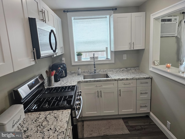 kitchen featuring dark wood-type flooring, white cabinets, an AC wall unit, stainless steel appliances, and sink