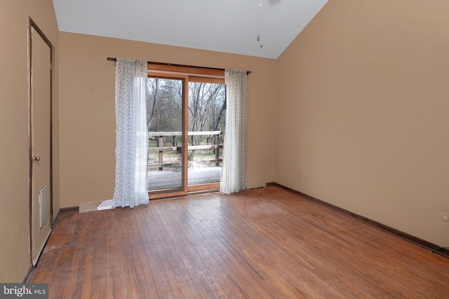 spare room featuring hardwood / wood-style flooring and lofted ceiling