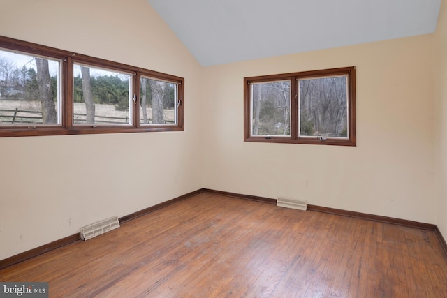 spare room featuring hardwood / wood-style floors and lofted ceiling