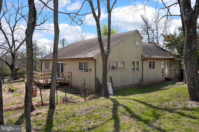 rear view of house featuring a lawn and a wooden deck