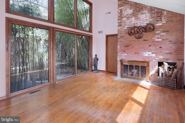 unfurnished living room with a brick fireplace, hardwood / wood-style floors, and high vaulted ceiling