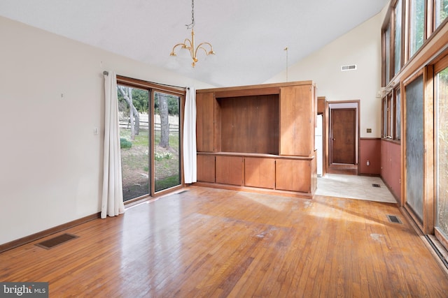 unfurnished room featuring high vaulted ceiling, light hardwood / wood-style floors, and a chandelier