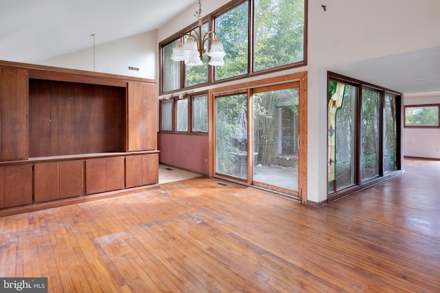 unfurnished living room with a chandelier, plenty of natural light, light wood-type flooring, and high vaulted ceiling