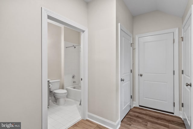 bathroom featuring lofted ceiling, hardwood / wood-style flooring, shower / tub combination, and toilet