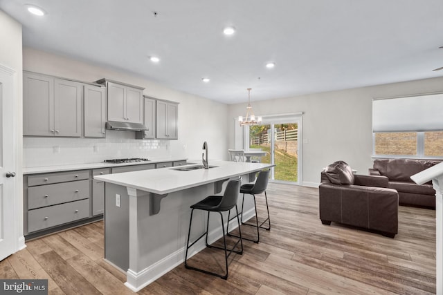 kitchen with an island with sink, light wood-type flooring, sink, and gray cabinetry