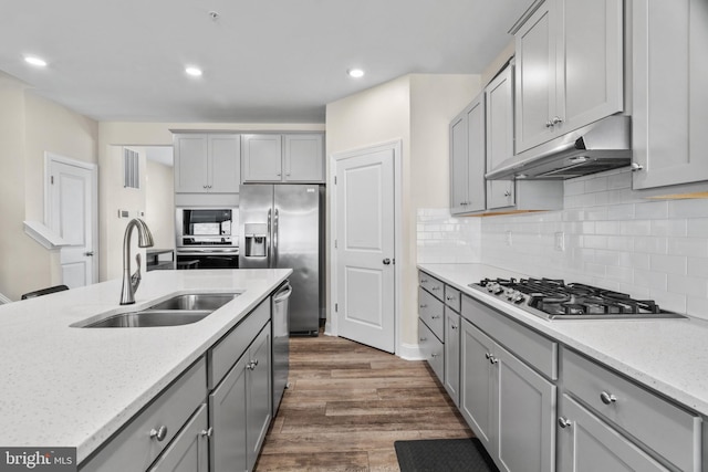 kitchen with appliances with stainless steel finishes, gray cabinetry, dark wood-type flooring, and sink