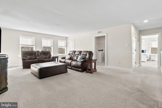 living room featuring washer / clothes dryer and light colored carpet