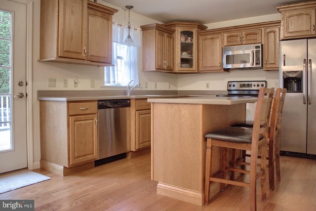 kitchen with light wood-type flooring, pendant lighting, stainless steel appliances, and plenty of natural light