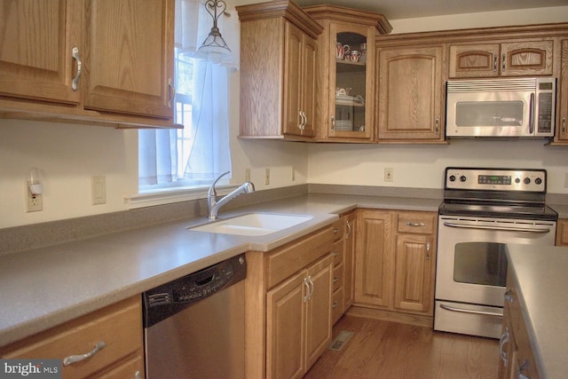 kitchen featuring appliances with stainless steel finishes, sink, dark wood-type flooring, and decorative light fixtures