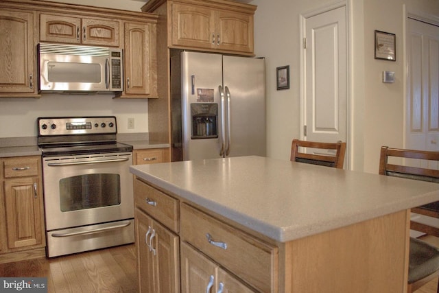 kitchen with appliances with stainless steel finishes, a center island, and light hardwood / wood-style flooring