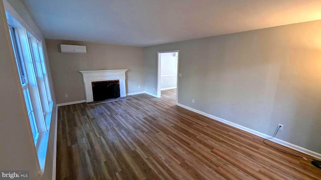 unfurnished living room featuring a wall mounted air conditioner and dark hardwood / wood-style flooring