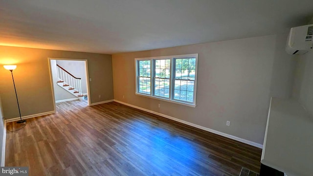 spare room with dark wood-type flooring and a wall mounted AC