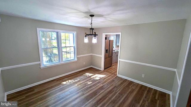 unfurnished dining area featuring a notable chandelier and hardwood / wood-style floors