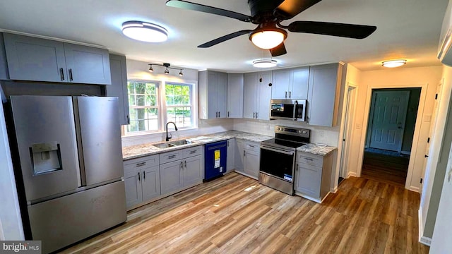 kitchen featuring light stone countertops, appliances with stainless steel finishes, sink, and ceiling fan