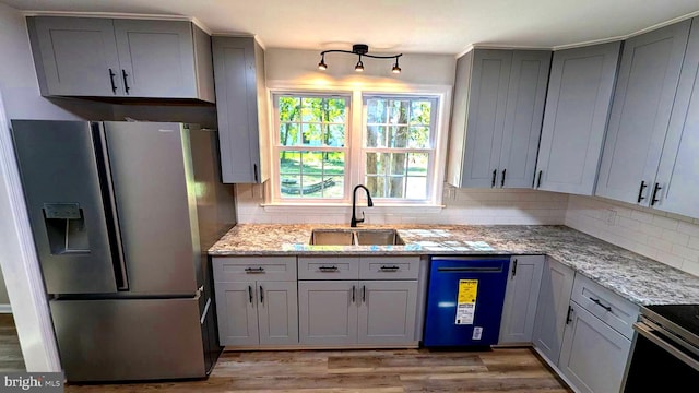 kitchen featuring stainless steel fridge, light stone countertops, sink, and light hardwood / wood-style floors