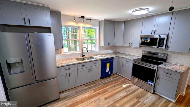 kitchen with sink, tasteful backsplash, light hardwood / wood-style flooring, stainless steel appliances, and light stone countertops