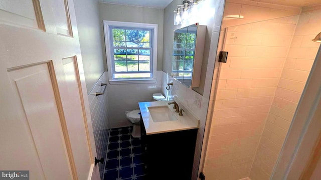 bathroom featuring walk in shower, vanity, tile walls, and toilet