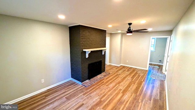 unfurnished living room with ceiling fan, a fireplace, and light wood-type flooring