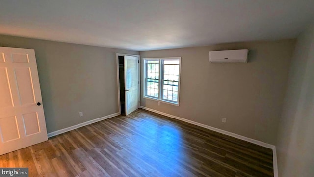 empty room featuring an AC wall unit and dark hardwood / wood-style flooring