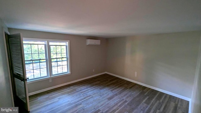 unfurnished room featuring a wall unit AC and dark hardwood / wood-style flooring