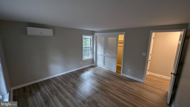 unfurnished bedroom with a closet, dark hardwood / wood-style floors, and a wall unit AC