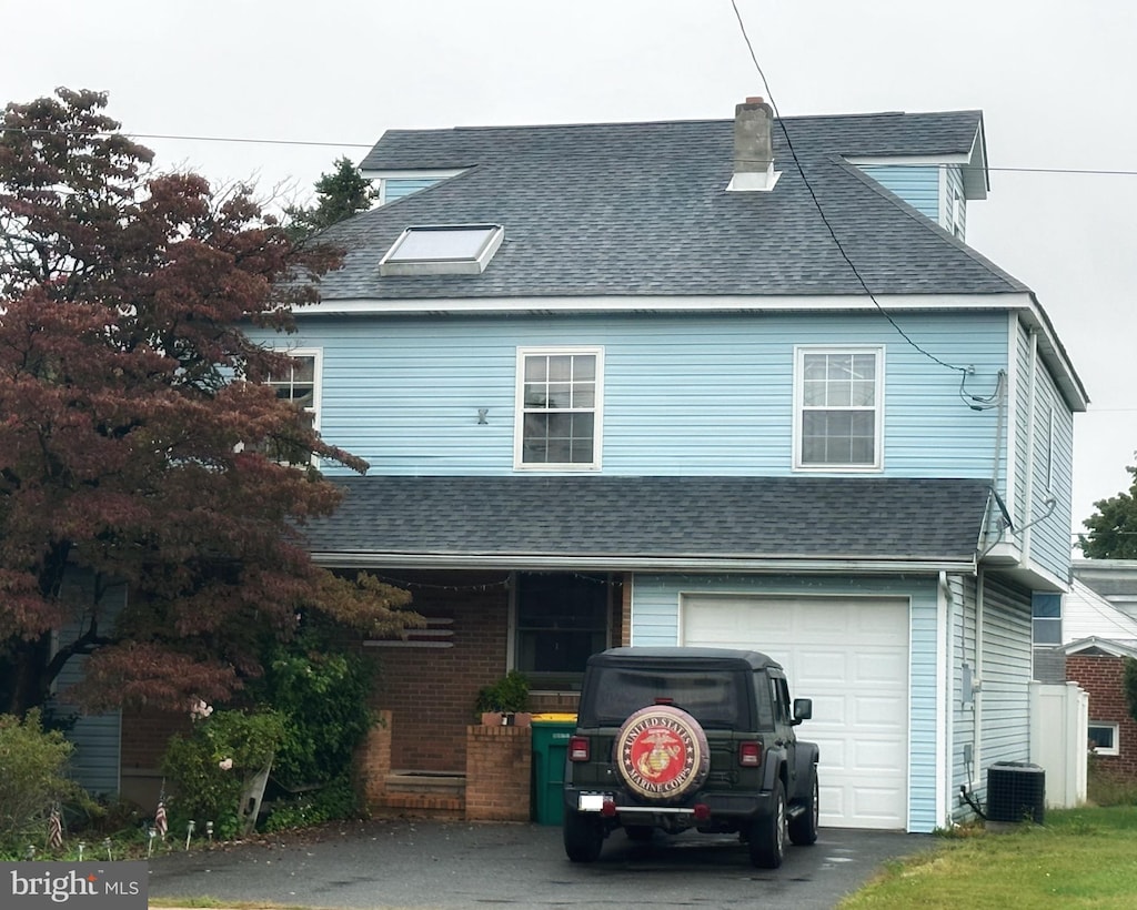 view of front of home with central AC unit and a garage