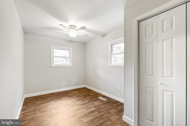 unfurnished room featuring hardwood / wood-style flooring, a wealth of natural light, and ceiling fan