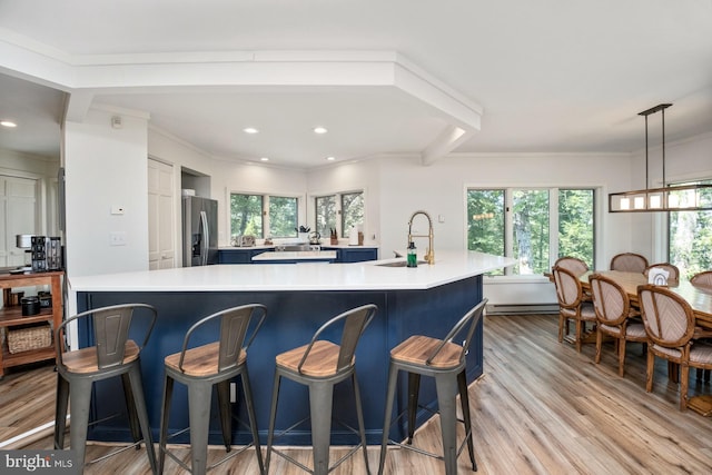 kitchen featuring pendant lighting, stainless steel refrigerator with ice dispenser, a large island with sink, and a wealth of natural light