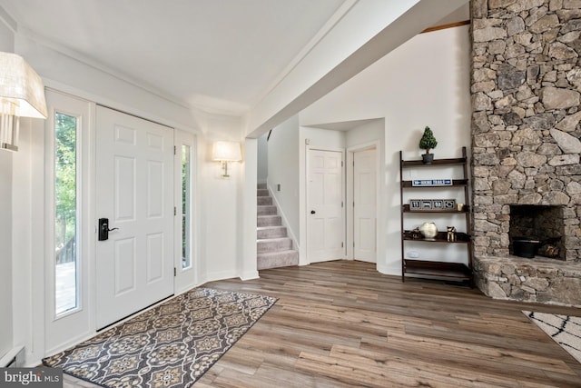 foyer with wood-type flooring and a stone fireplace