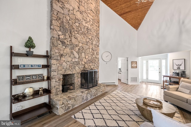 living room featuring light wood-type flooring, wood ceiling, a stone fireplace, and high vaulted ceiling