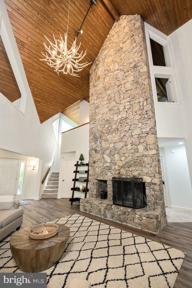 unfurnished living room featuring wood ceiling, beam ceiling, wood-type flooring, a stone fireplace, and high vaulted ceiling