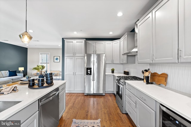 kitchen with hardwood / wood-style flooring, hanging light fixtures, stainless steel appliances, beverage cooler, and light stone counters