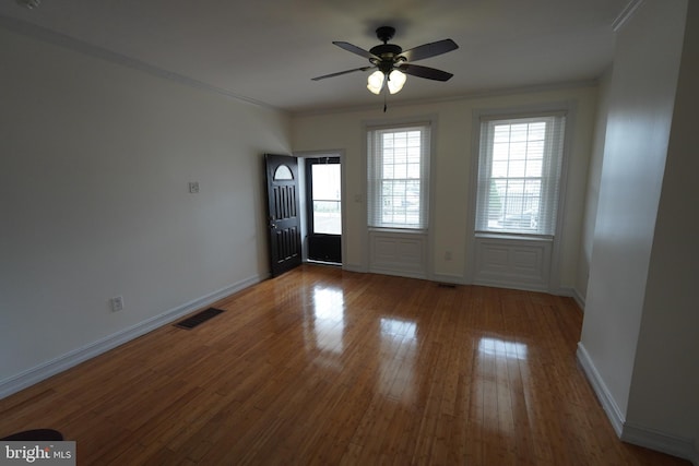 empty room with ornamental molding, wood-type flooring, and ceiling fan