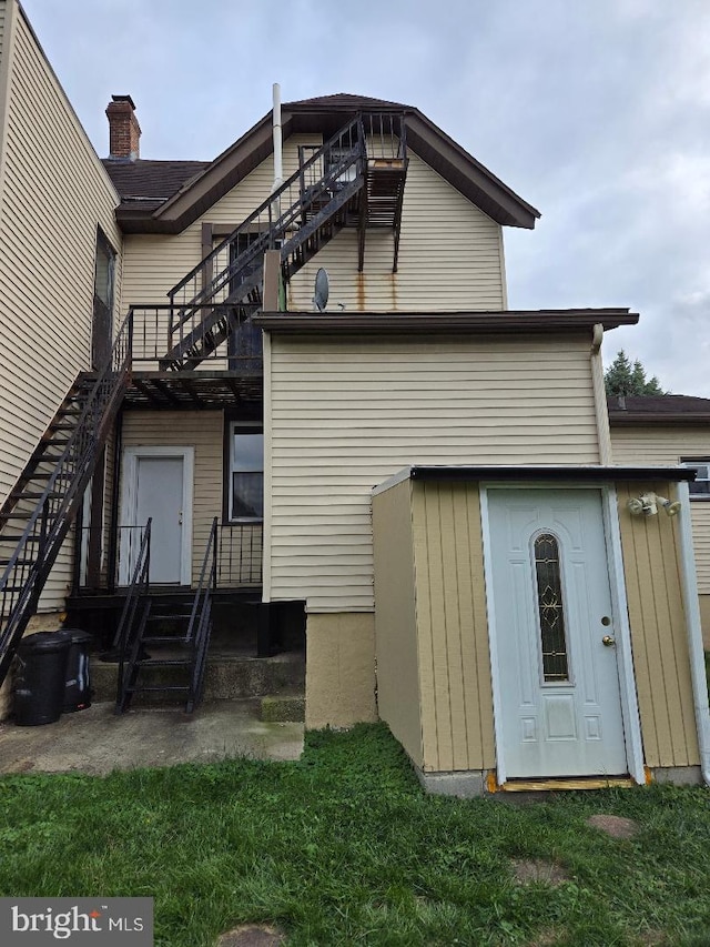 back of property featuring a deck and a lawn