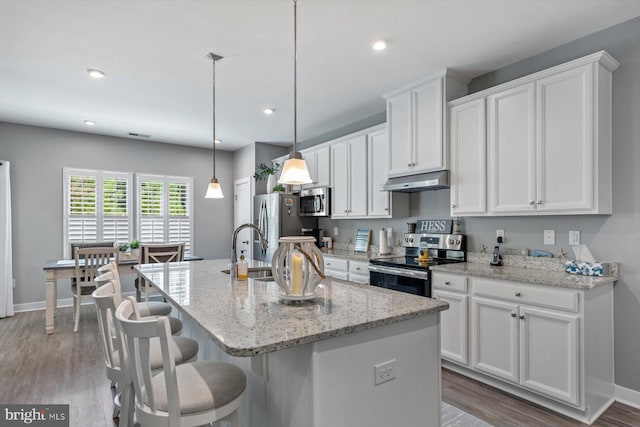 kitchen featuring pendant lighting, a center island with sink, appliances with stainless steel finishes, and light wood-type flooring