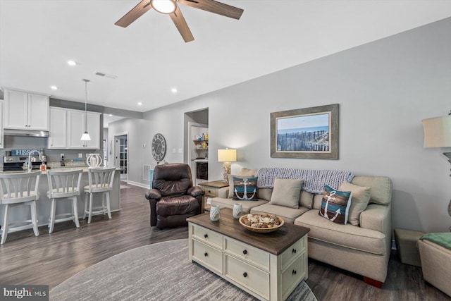 living room with ceiling fan and dark wood-type flooring